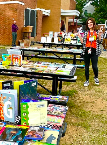A teacher is standing next o the free books station.