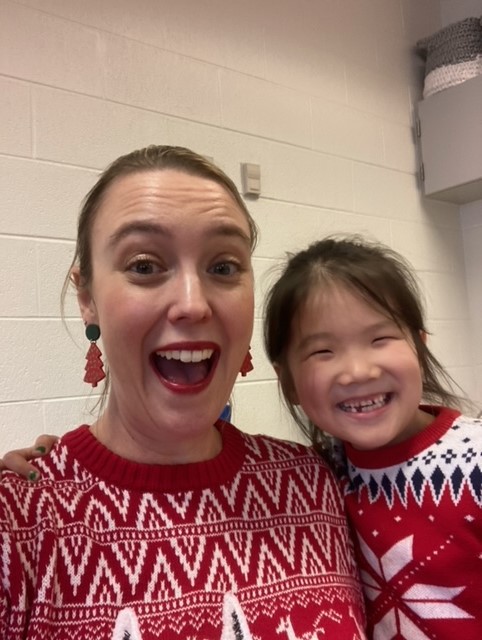 A teacher and a student wearing Christmas sweatshirt.