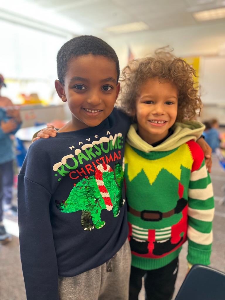 Two students wearing elf sweaters.
