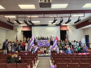 Military child celebration in the auditorium; purple balloon, bears from all branches, military banner.