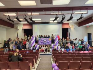 Military child celebration in the auditorium; purple balloon, bears from all branches, military banner.