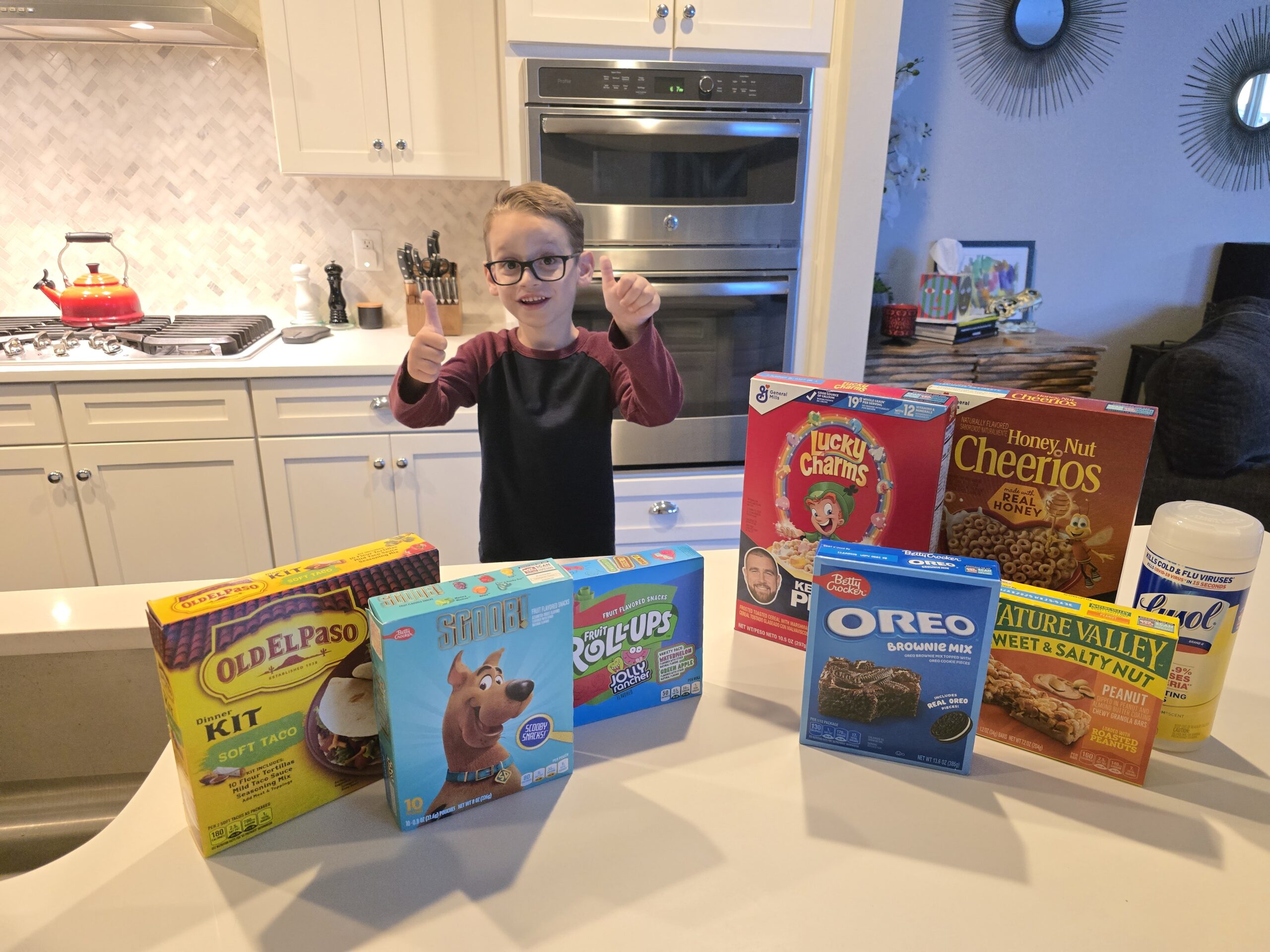 A student standing in a kitchen with boxes of cereal.