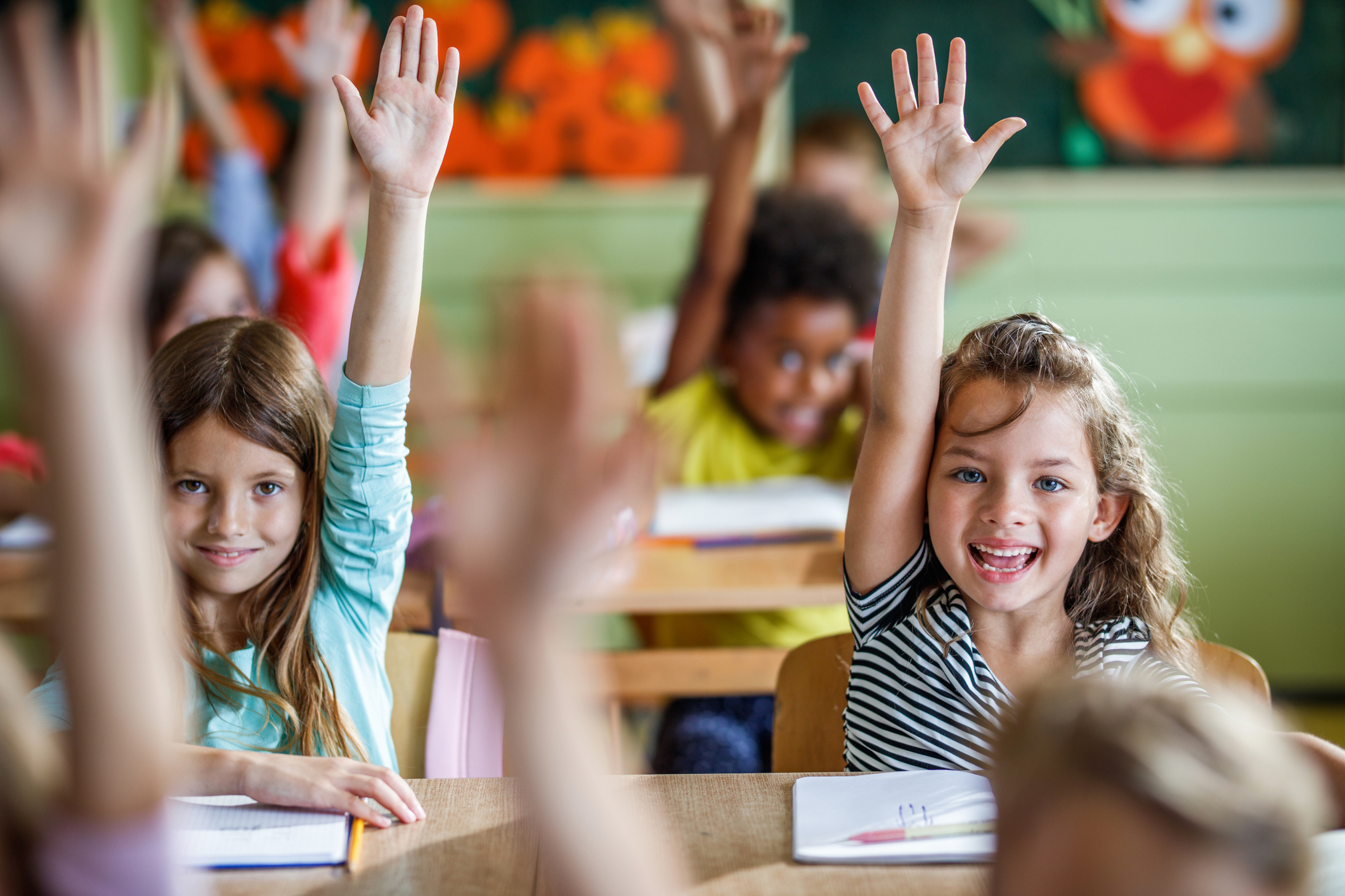 students seat at desk; raising hands