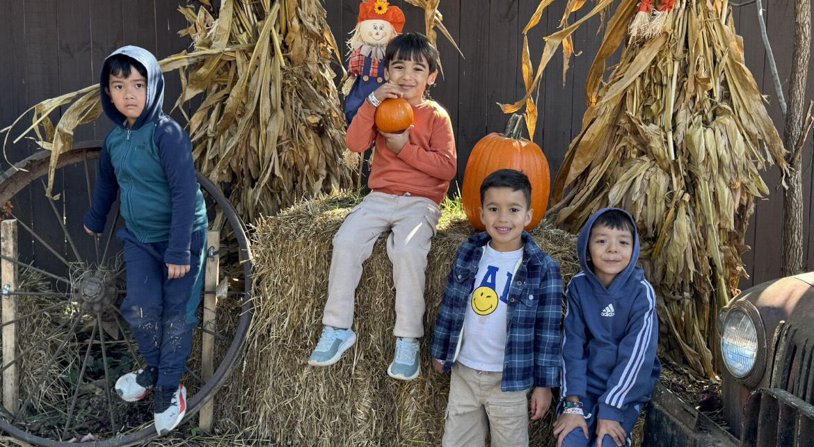 Students posting and sitting on top of hay stack; holding pumkin