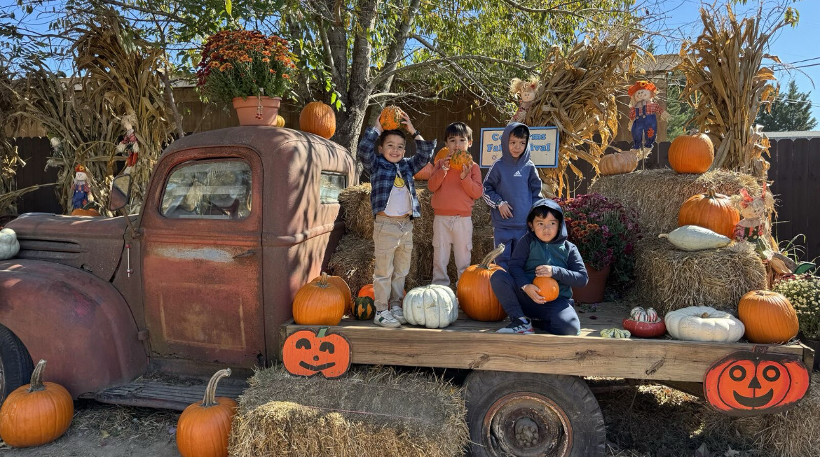 Students standing on a pack farm trucks holding pumpkins
