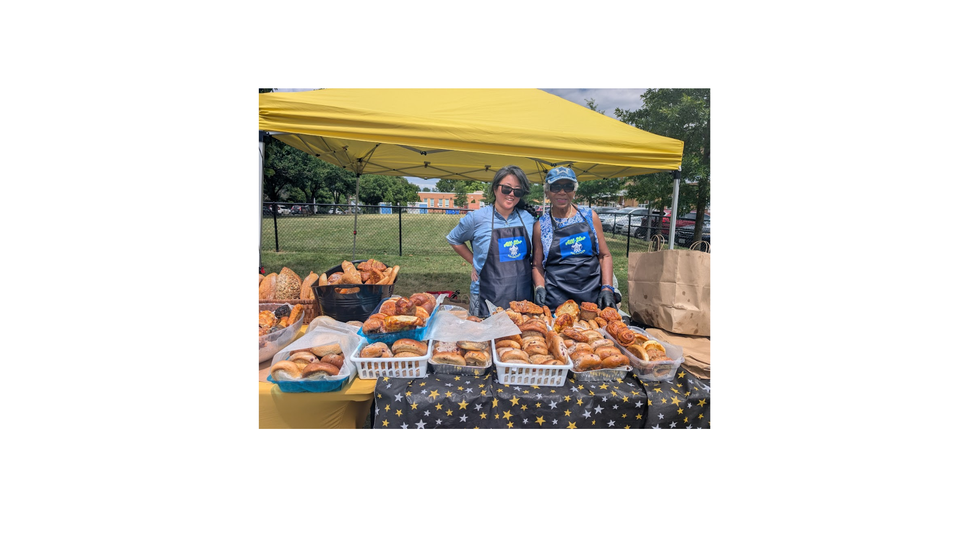 Monday share table at Hoffman-Boston; two volunteer standing behind table filled with different types of bagels.