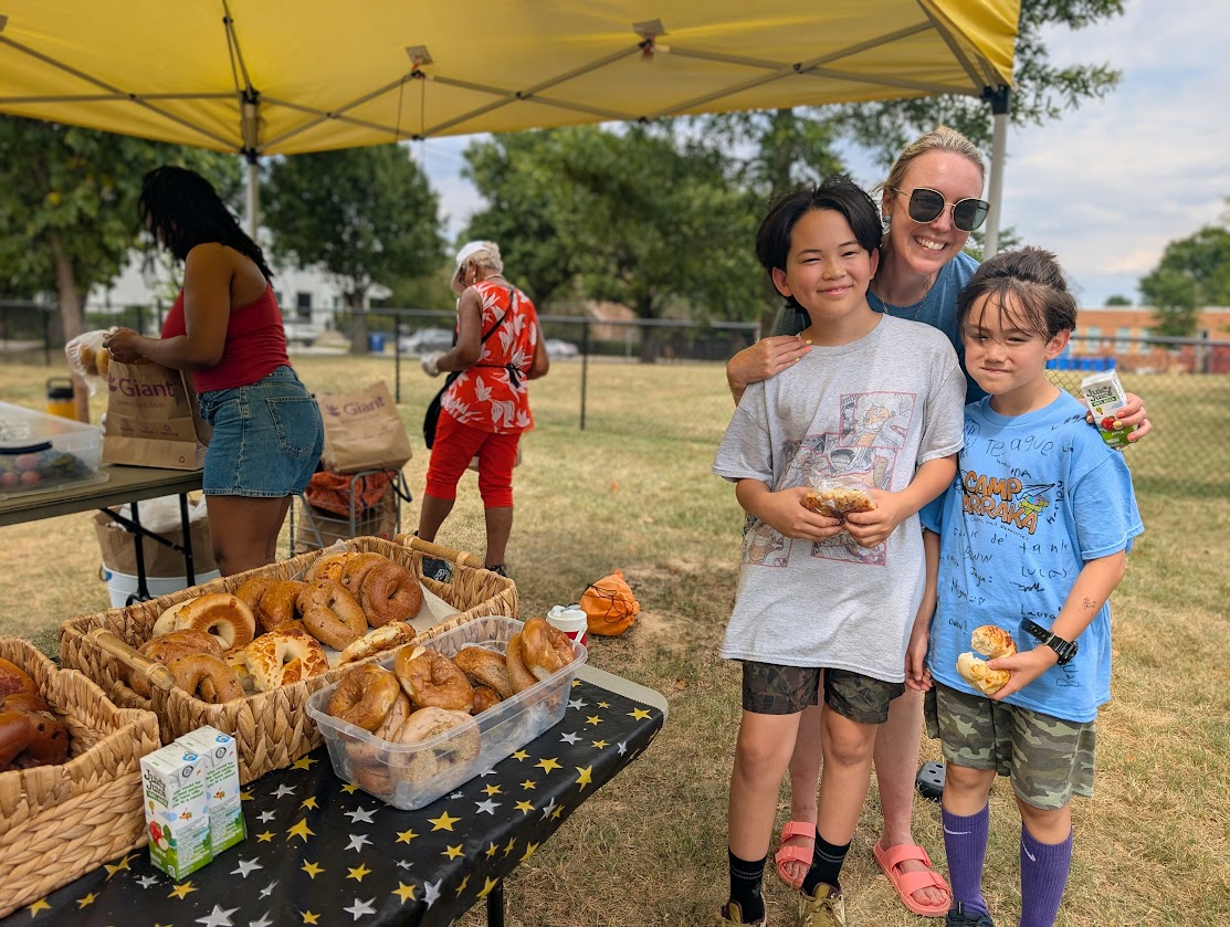 Teacher is posting for picture with two students next to Monday share table tent.