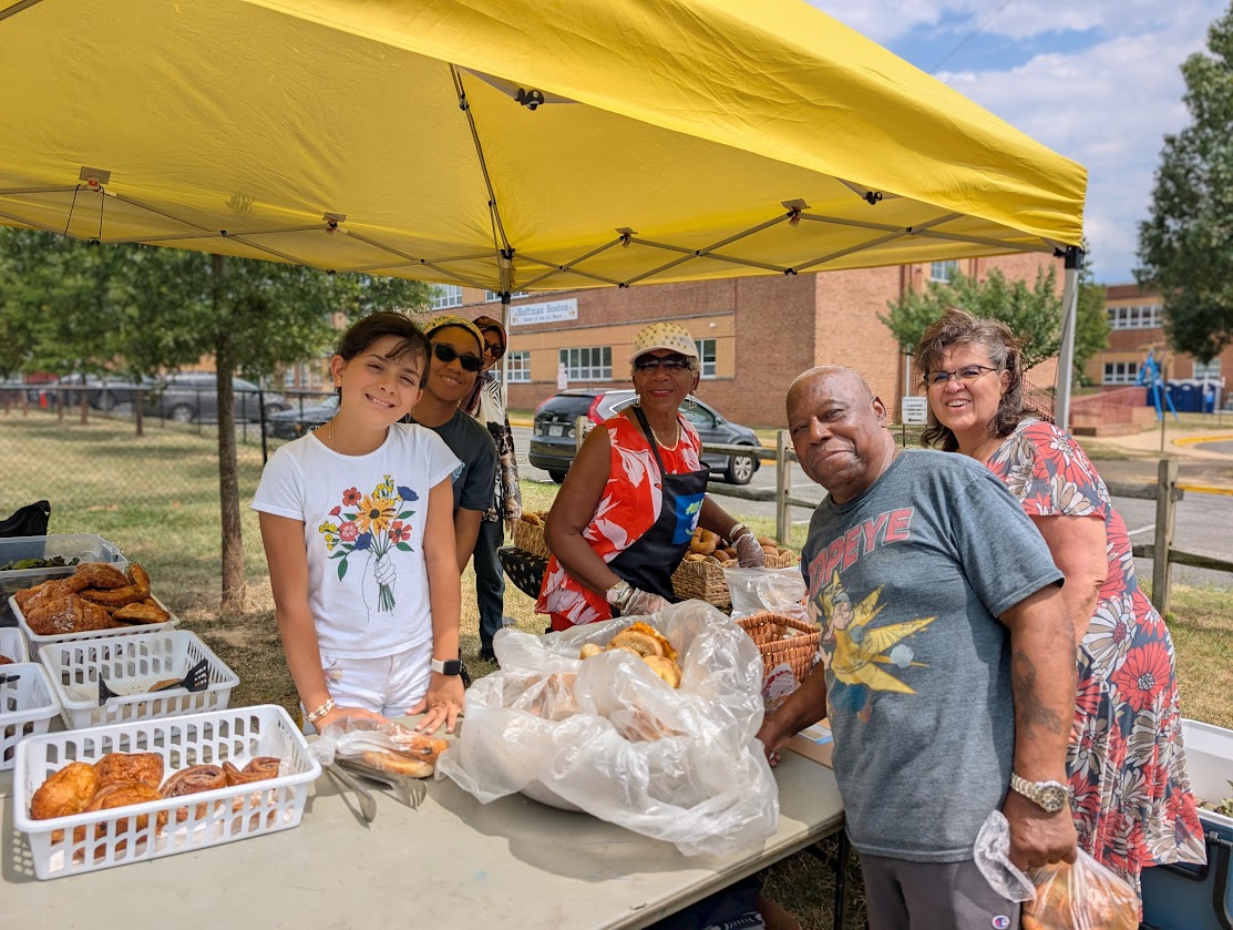 Volunteers, students and staff member posting for picture at Monday share table.